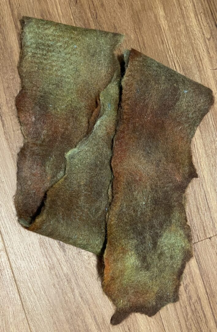 A piece of green and brown fabric on top of a wooden floor.