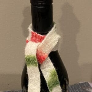 A bottle of wine with a knitted scarf around it.