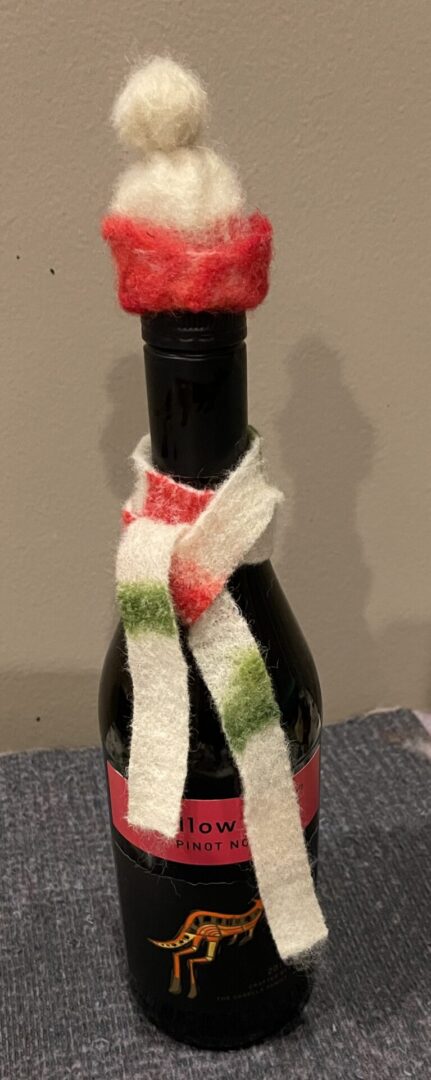 A bottle of wine with a knitted scarf around it.