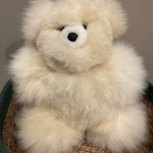 A white teddy bear sitting on top of a basket.