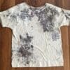 A white shirt with some black and brown leaves on it