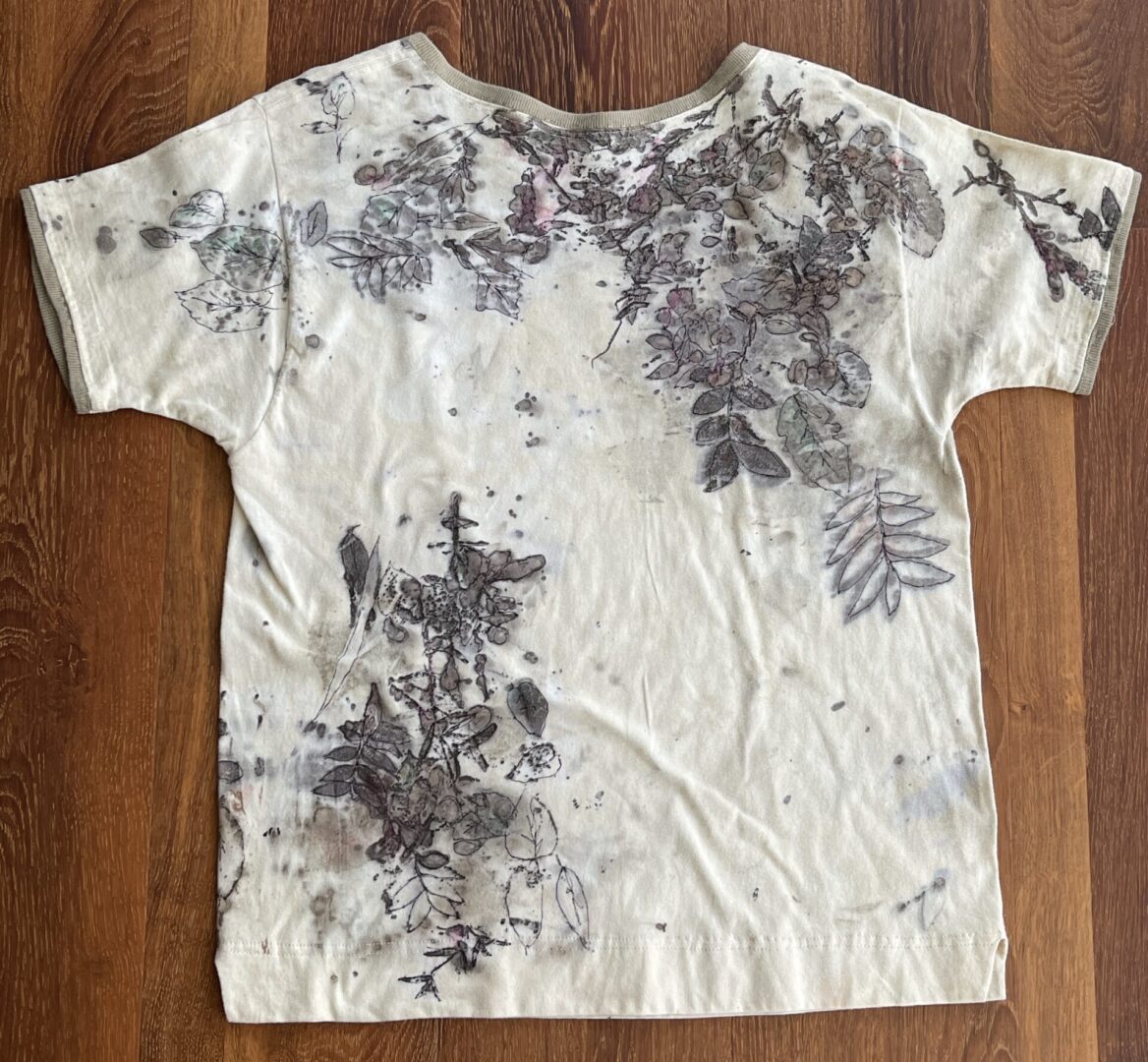 A white shirt with some black and brown leaves on it