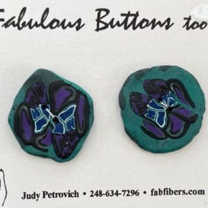 A pair of buttons with purple and blue flowers on them.