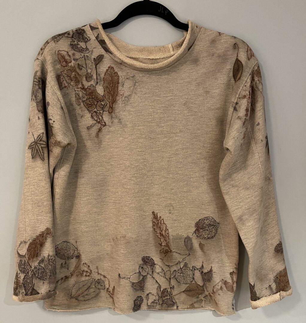 A beige sweater with brown flowers on it.