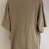A tan shirt is shown with the back of it.