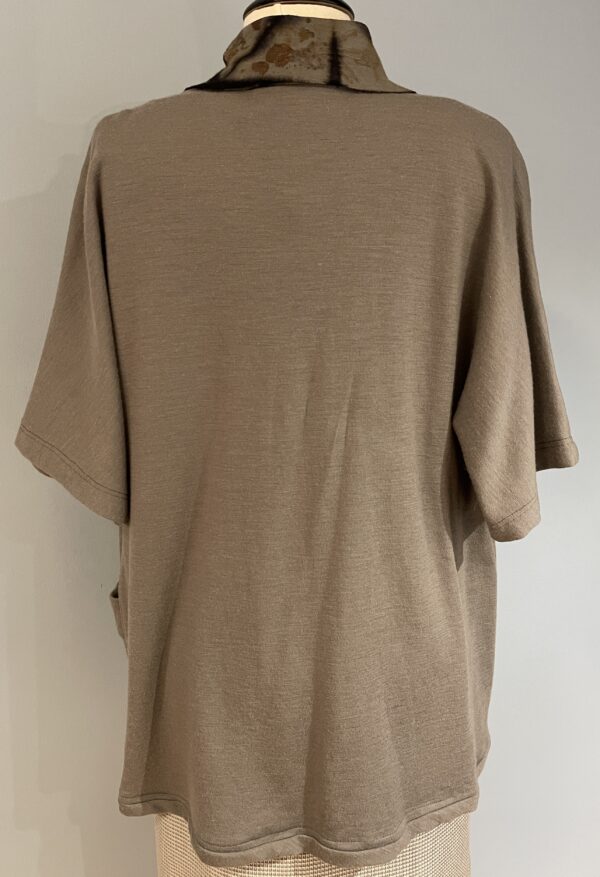 A tan shirt is shown with the back of it.