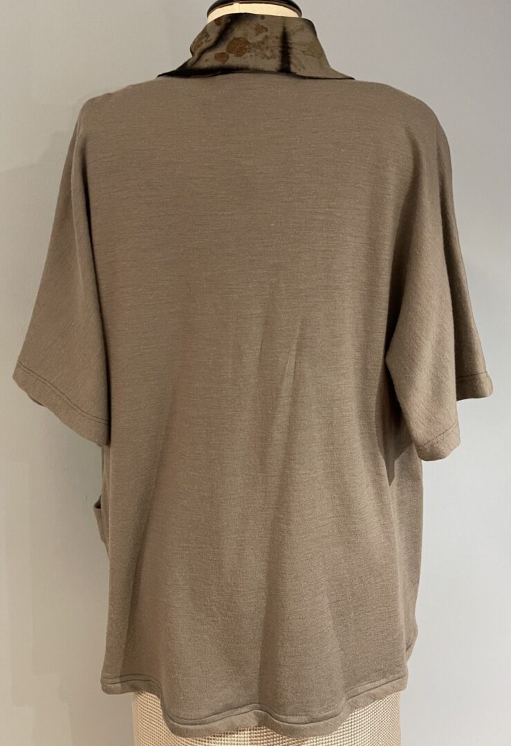A tan shirt is shown with the back of it.