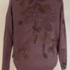 A purple sweater with brown leaves on it.