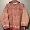 A red and white hooded sweater is hanging on the wall.