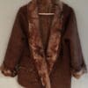 A brown coat with fur on it hanging from a clothes line.