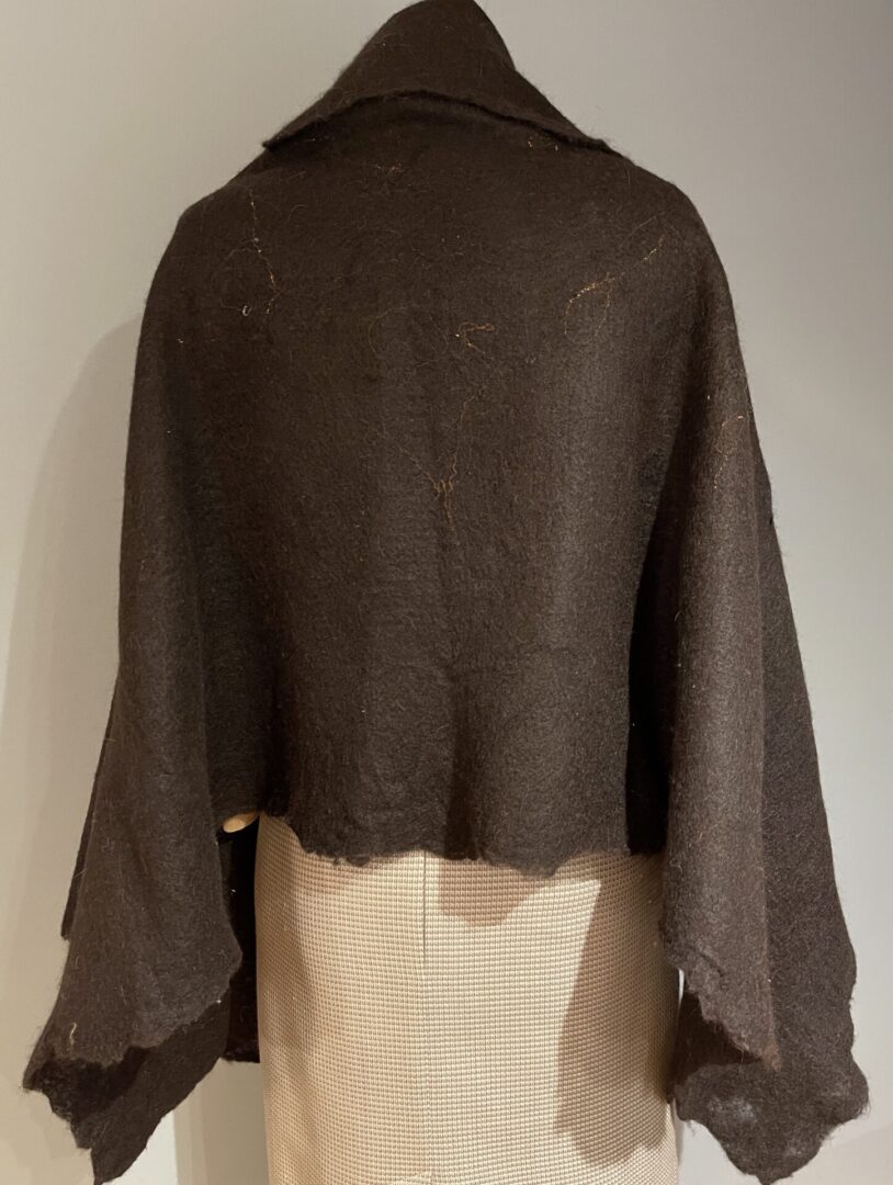A brown shawl is draped over the back of a mannequin.