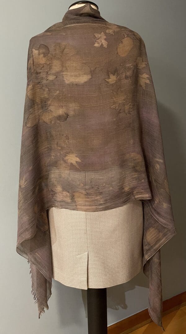 A brown and beige poncho draped over the shoulders of a mannequin.