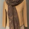 A woman wearing a tan top and a brown scarf.