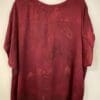 Burgundy blouse on hanger, back view.