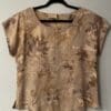 Tan leaf-print shirt on hanger.
